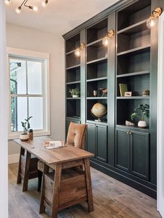 a wooden table sitting in the middle of a living room next to a book shelf