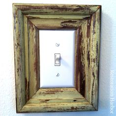 an old light switch cover is hanging on the wall in a rustic frame with peeling paint