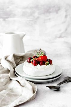 a plate topped with cake covered in whipped cream and strawberries next to a pitcher