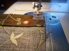 the sewing machine is next to an embroidered piece of fabric with a flower design on it