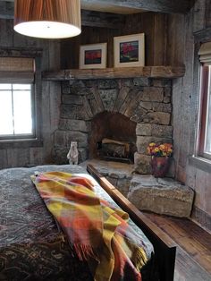 a bedroom with a stone fireplace in the corner and a blanket on the bed next to it