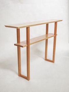 a wooden table with two benches underneath it on a white background in front of a wall