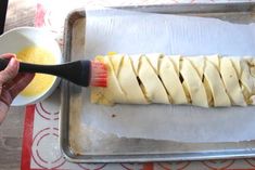 a person using a brush to spread the dough on top of an uncooked pastry