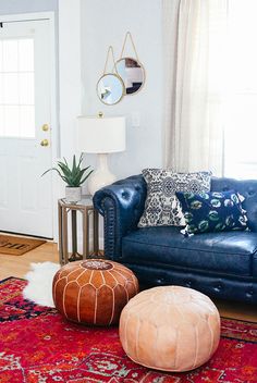 a living room with blue leather couches and poufles on the rugs