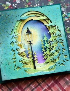 a close up of a card with trees and a street light in the background on a table