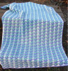 a blue and white blanket sitting on top of a wooden bench