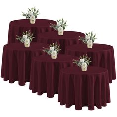 six burgundy round tables with white flowers and greenery on each tablecloth, set against a white background