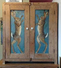 an old wooden cabinet with two rabbits painted on it