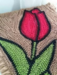 a crocheted blanket with a red rose on it