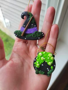 two handmade witch hats are hanging from the palm of a person's hand