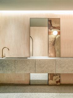 a bathroom sink sitting under a large mirror next to a wall mounted faucet