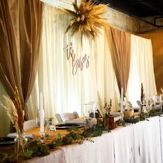 the table is set for an event with white linens and greenery on it