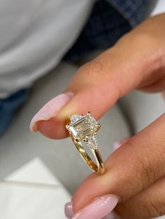 a close up of a person holding a ring with a diamond on the middle finger