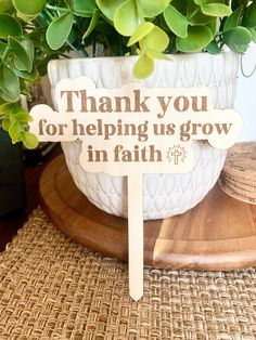 a wooden sign that says thank you for helping us grow in faith on a table next to a potted plant