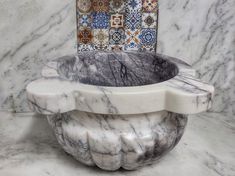 a white marble bowl sitting on top of a counter next to a wall with tiles