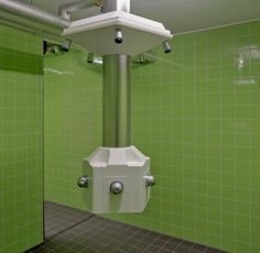 a green tiled bathroom with a white urinal