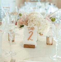 the table numbers are displayed on small vases with flowers in them, along with wine glasses and silverware