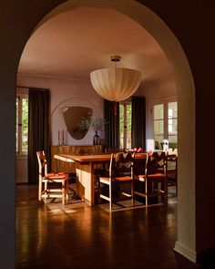 an archway leading into a dining room with wooden chairs and table in the foreground