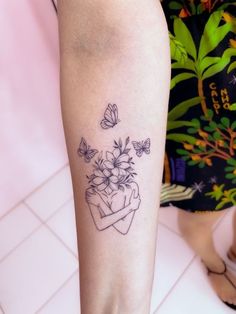 a woman's leg with flowers and butterflies tattoo on her left calf area, next to a tiled floor