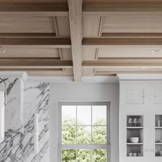 a kitchen with marble counter tops and white cabinets, along with an open window that looks out onto the trees outside