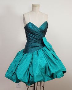 An 80s Designer vintage Emerald green corsseted boned strapless mini dress with full  circle skirt.  Bubble skirt with a lined circle attachment to hold the amazing look. The bodice has a pleated gathered cinched waist.  A back hidden zippen for clousre. Boning and corseted with Criline for the skirt.   Fully lined.  Huge attached bow on the side. Label ~ FRANCAIS By Huey Waltzer  Size 4 Color  `~ Emerald green Fabric ~ Tafetta , Shmimmer facric lightweight .  Measurements  Bust ~34 The bust is Fitted Green A-line Strapless Dress, Vintage Knee-length Prom Dresses, Vintage Mini Length Corset Dress For Party, Vintage Summer Party Corset Dress, Vintage Fitted Strapless Dress For Party, Fitted Retro Strapless Dress, Retro Fitted Strapless Dress, Vintage Style Mini Dress For Costume Party, Vintage Mini Dress For Costume Party