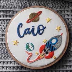 the embroidery on this hoop has an image of a rocket ship, planets and stars