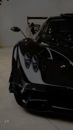 a black and white sports car is parked in a showroom with its hood up