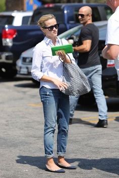 a woman in white shirt and jeans holding a green object while standing next to other people