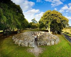 a stone structure in the middle of a grassy area with trees and grass around it