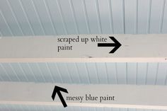 two signs pointing in opposite directions on the ceiling with white paint and blue paint underneath