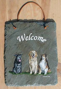 a welcome sign with three dogs painted on it