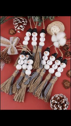 snowmen and pine cones are arranged on a red surface with twine, burlap