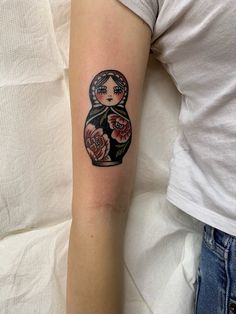 a woman's arm with a tattoo on it that has a doll and flowers