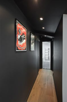 an empty hallway with posters on the wall and wood flooring in front of it