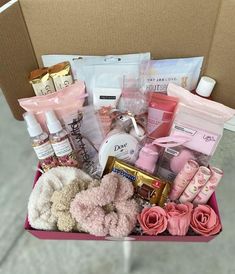 a pink box filled with lots of different items and flowers on top of a table