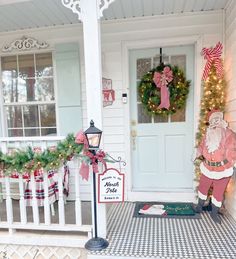 a front porch decorated for christmas with wreaths and decorations on the door, santa clause