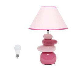 a pink lamp sitting on top of a table next to a white light bulb with a pink shade