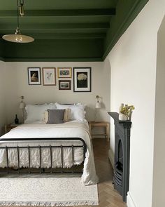 a bedroom with green painted ceiling, white bedding and pictures on the wall above it