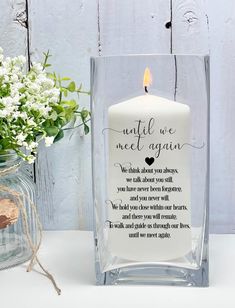 a candle that is sitting next to a vase with flowers in it and a message on the front