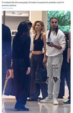 a man with dreadlocks standing next to a woman in ripped jeans and black top