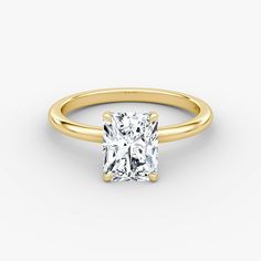 a yellow gold engagement ring with a princess cut diamond in the center, on a white background