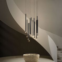 a modern chandelier hanging from the ceiling in a room with white walls and stairs