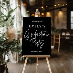 a welcome sign in front of a wooden easel with flowers and greenery on it