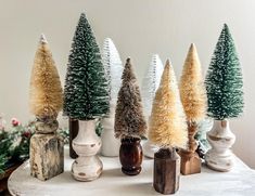 small christmas trees are lined up in vases