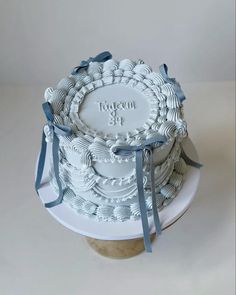 a white cake with blue ribbon on top