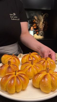 a person is placing small pumpkins on a plate