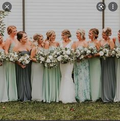 a group of women standing next to each other in front of a white wall holding bouquets