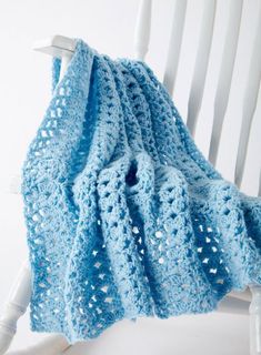 a blue crocheted blanket sitting on top of a white chair