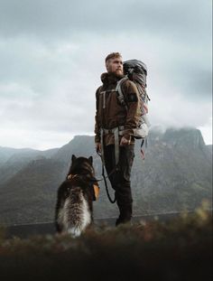 a man with a backpack and his dog on a mountain trail looking at the camera