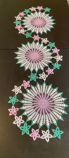 three rows of crocheted doily sitting on top of a black tablecloth